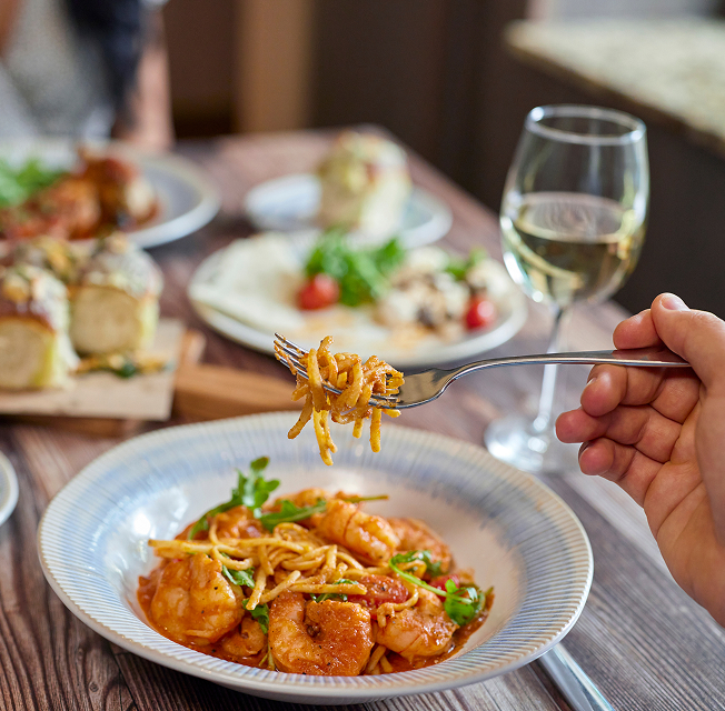 A shrimp and pasta dish, accompanied by white wine