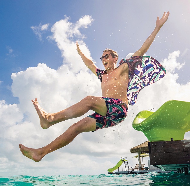 A man flies into the water off of a water slide