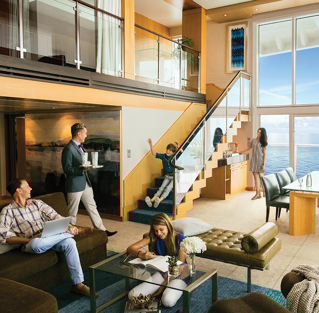 A family relaxes in the Royal Suite, a two-level berth featuring a lounge area and a stairway up to bedrooms, as a server delivers them drinks